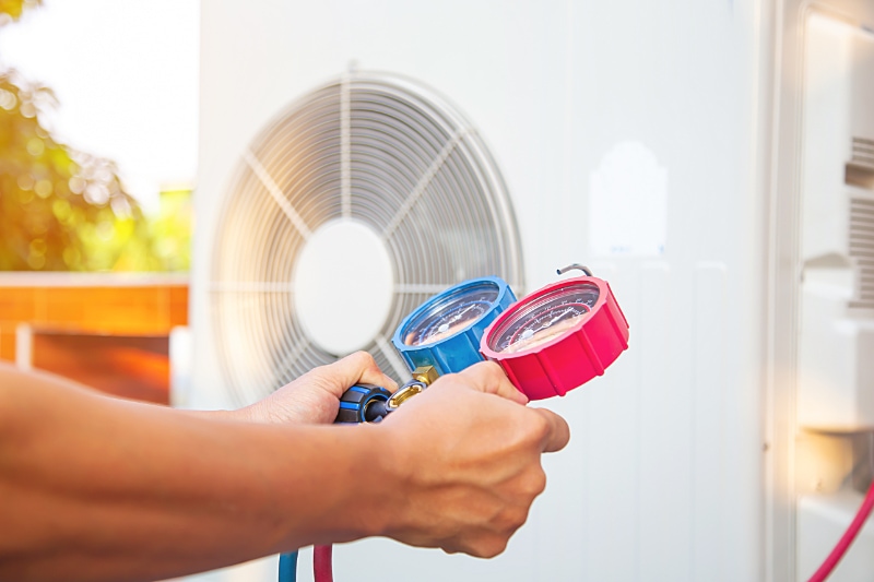 Air Conditioners Versus Heat Pumps. Hands of Technician are using a measuring tool to check Vacuum pump evacuates air for air conditioner.