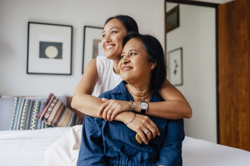 female embracing her mother while they are looking away.