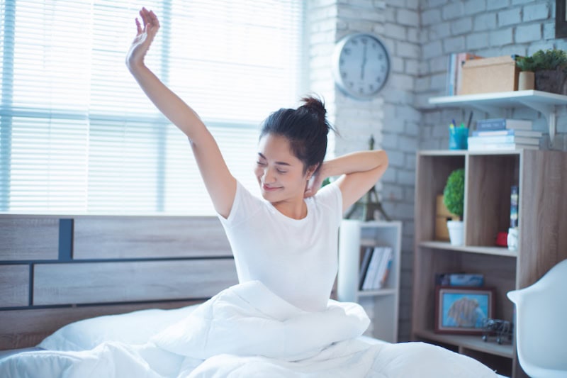 Woman waking up and stretching in bed.