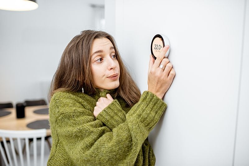 Why Is My Heat Pump Turning On and Off Frequently? - Woman Adjusting the Termostat.