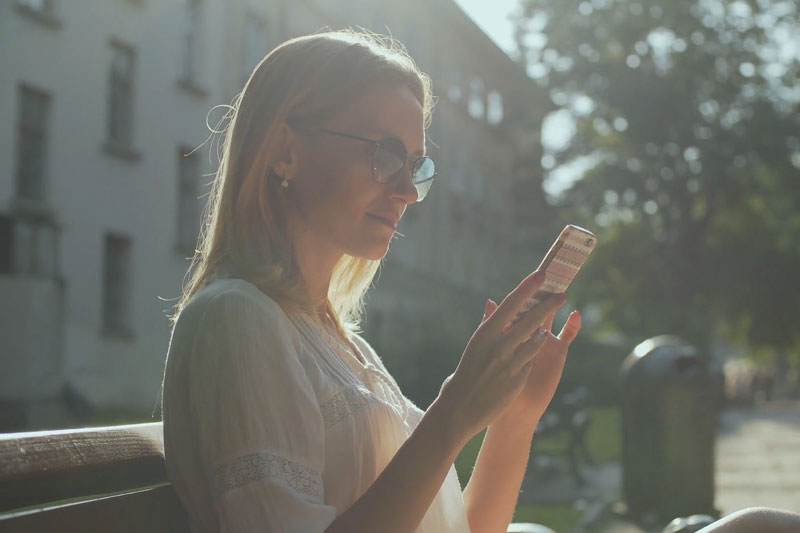 Are Wi-Fi Thermostats Cost-Effective? Woman changing her thermostat settings from her phone.